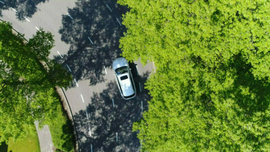 aerial view of electric car being driven through green trees